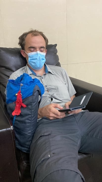 Benjamin s'endormant son téléphone à la main dans l'aéroport de Guatemala City.