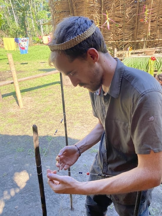Benjamin très concentré pour fabriquer son bracelet avec les graines de la jungle
