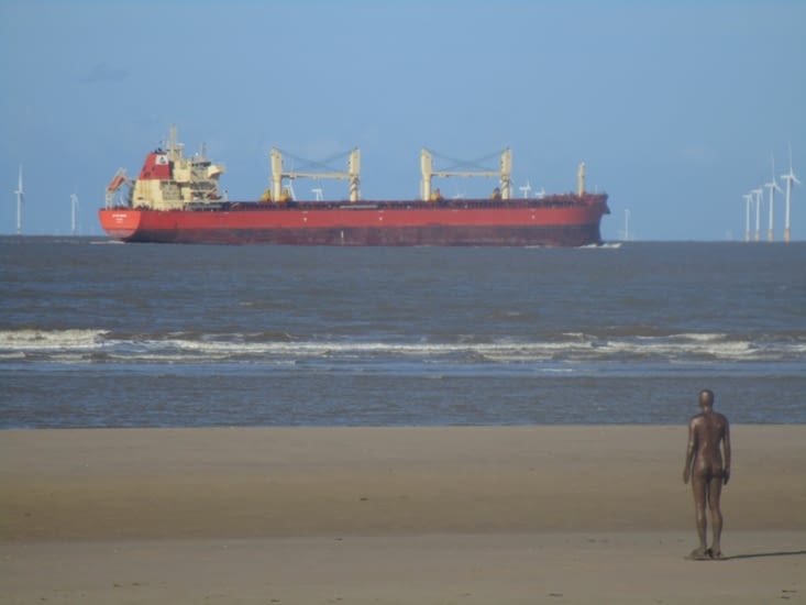 une des cent statues sur la plage contemple la Mersey et les bateaux