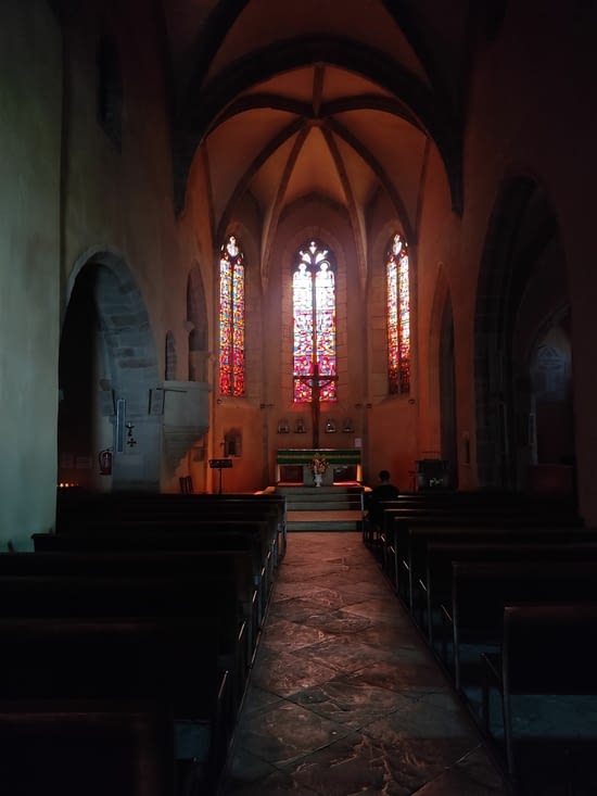 L'intérieur de l'église avec les vitraux qui donnent une lumière rosée, belle ambiance