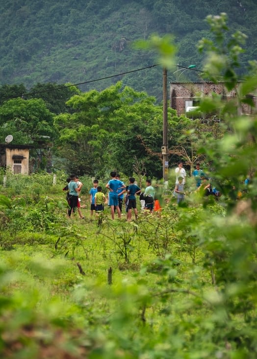 Les enfants du village jouant au foot sur un terrain vague enherbé