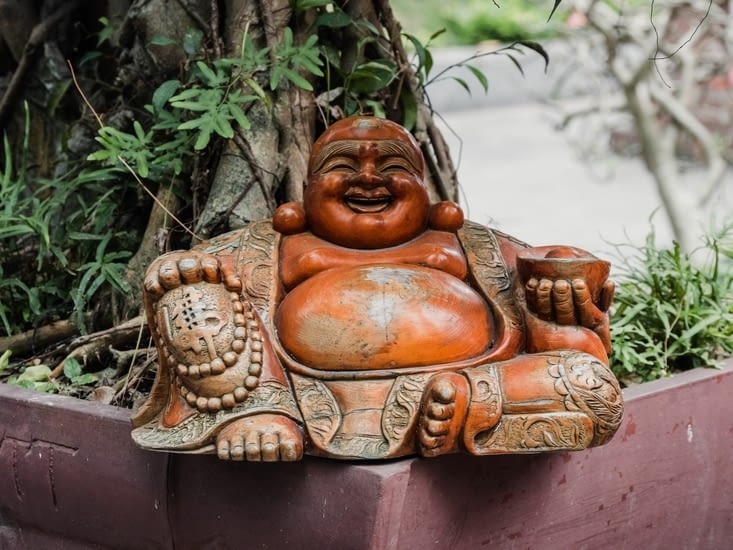 Un bouddha en bois au ventre usé par les mains venues chercher la prospérité
