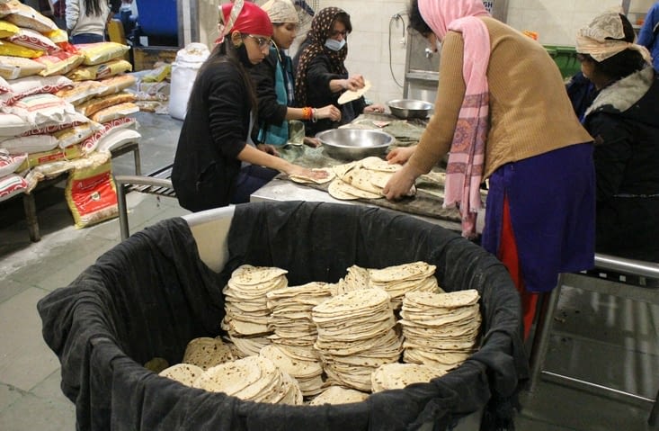 Une fois cuits, les chapatis sont enduits d'huile par ces jeunes filles