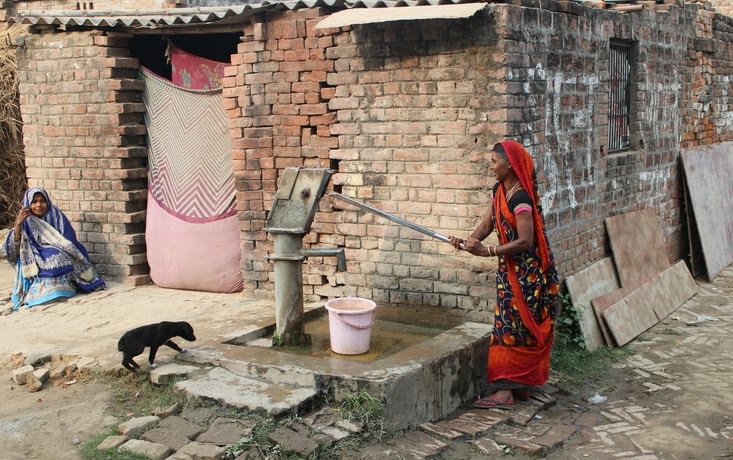 une femme tire de l'eau à la pompe