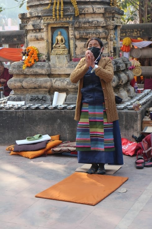 une femme en costume traditionnel tibétain s'apprête à se prosterner