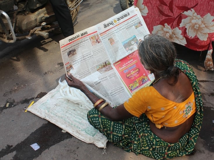 Une dame qui lit tranquillement son journal entre deux voitures