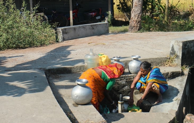 des femmes prenant de l'eau à la fontaine