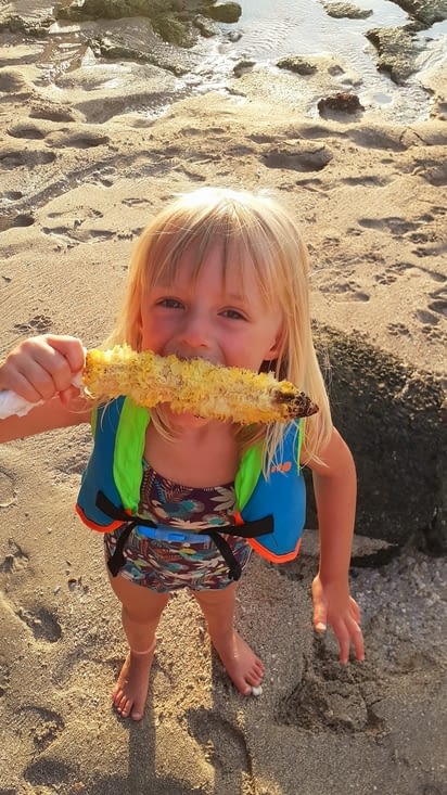 Zézouille qui mange du maïs grillé sur la plage