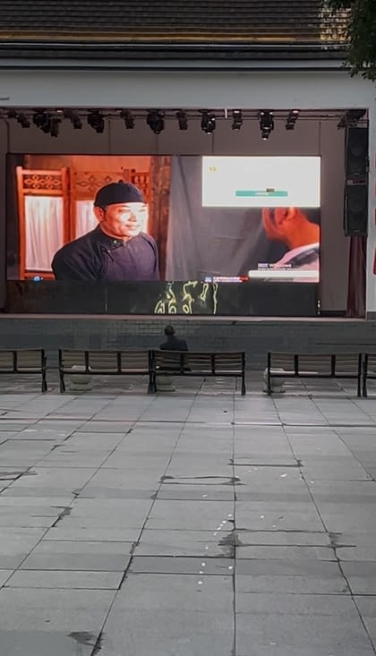 Un homme seul sur une place, regarde un film