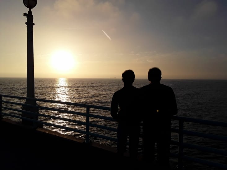 Romain et sebastien regardant le soleil se coucher sur l ' océan pacific