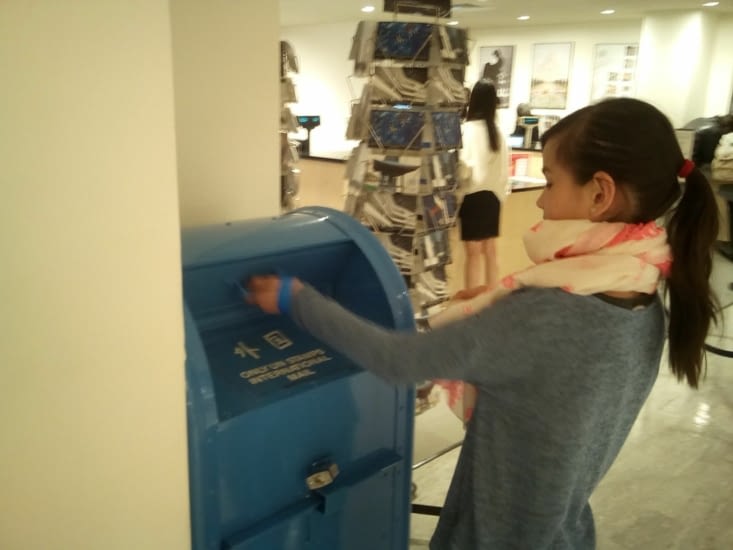 Léna s'occupe de poster les cartes postales.