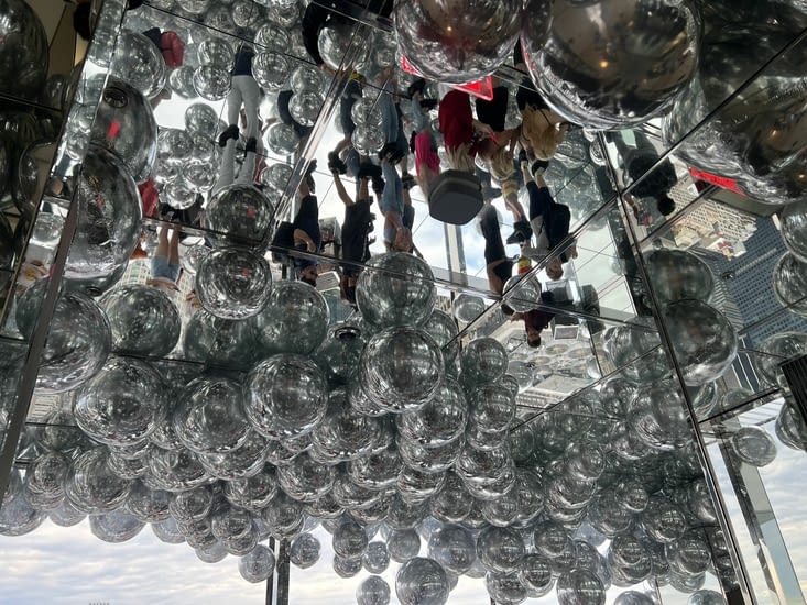 Un étage avec des ballons miroirs qui flottent, le sol plein de miroirs