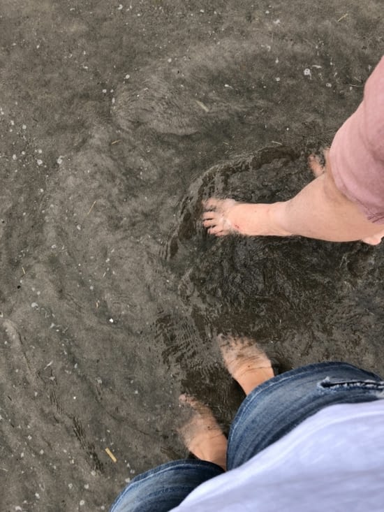 Les Pieds dans l'eau sur cette plage de sable noir