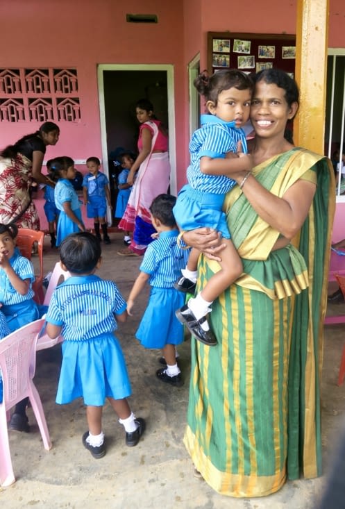 La directrice de l’école, qui porte dans ses bras Tilanya, la fille d’Eranga.