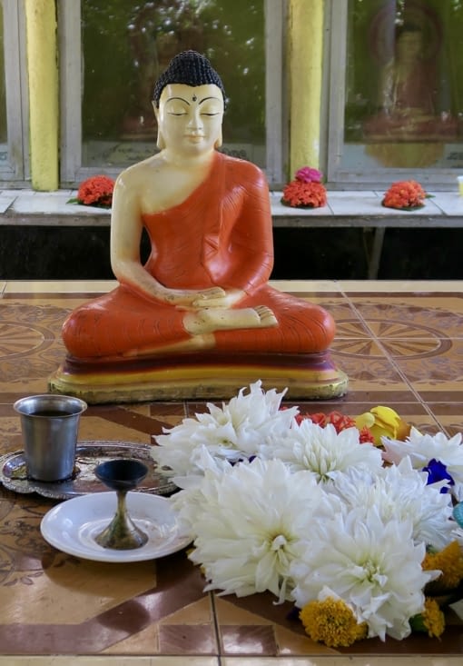 Devant l’entrée du temple, une petite statue de Bouddha, avec les offrandes