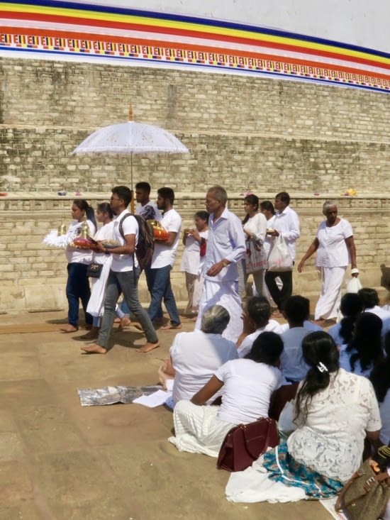 Les fidèles font le tour du dagoba en portant des offrandes, en chantant et priant.