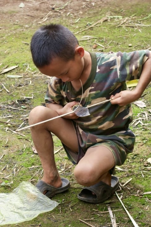 Celui-ci découpe un petit bambou pour faire l’armature d’un cerf-volant.