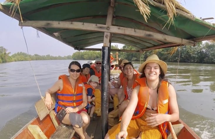 À plusieurs sur un petit bateau en bois, qui tire les kayaks jusqu’au départ de la balade.