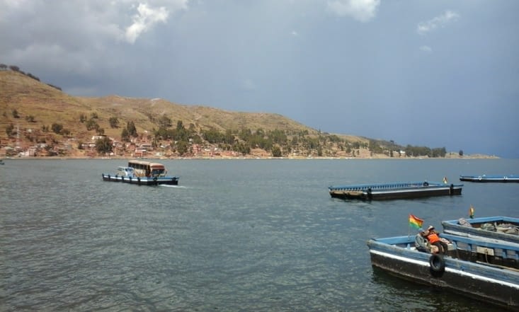 Sur le chemin de la Paz. Le bus traverse un détroit du lac Titicaca sur une barge et les passagers sur d'autres bateaux.