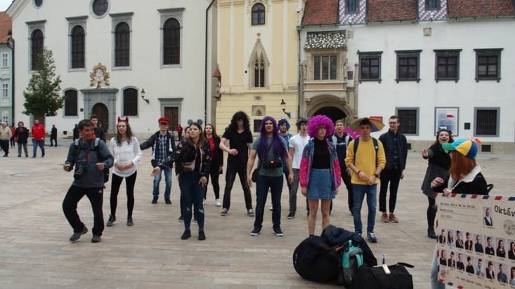 Un groupe d'étudiants danse sur la place, un touriste asiatique s'est mélé à eux