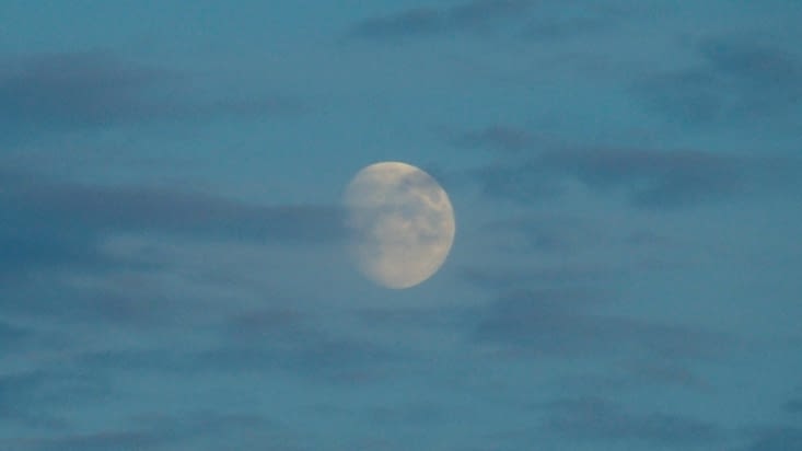 À travers les nuages, la lune tente de s'illuminer.