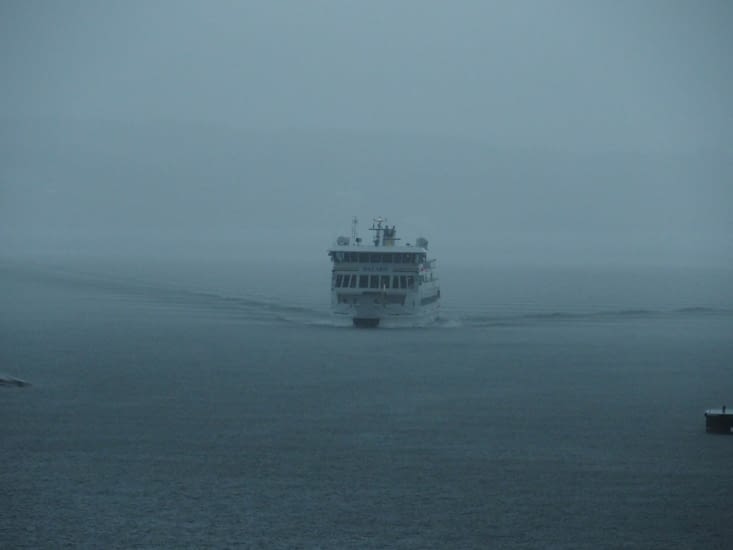 Au loin un remorqueur tracte un bateau sortant de la brume.