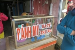 Eux, on devine ce qu'ils cuisinent. Lisez le avec l'accent vietnamien. Dans la série reste du colonialisme français,  on trouve par exemple: 'Sing-gum, socolat,complet veston, gara oto (mon préféré), kafe kem' et bien d'autres.